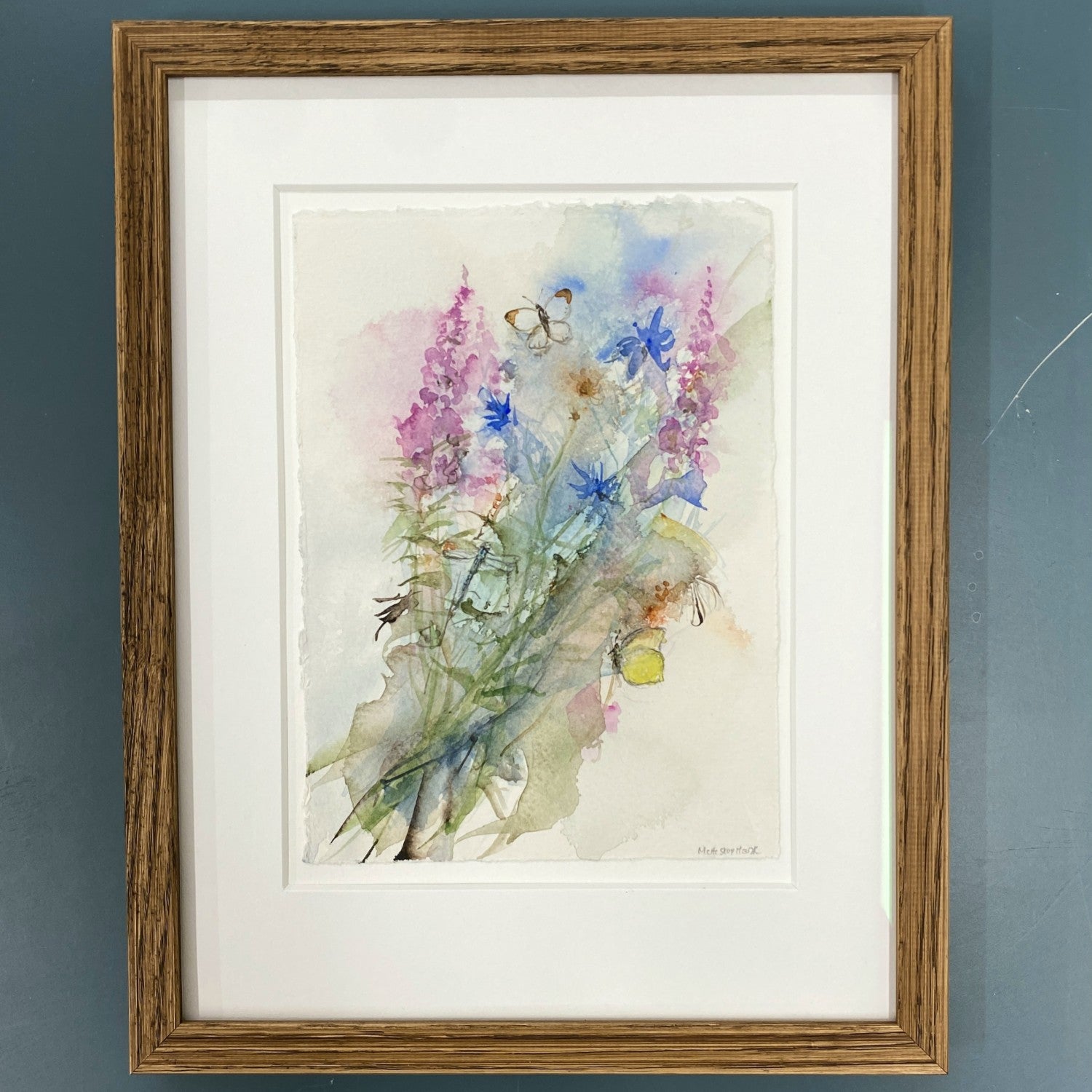 Akvarel med blomster gederams og kornblomst, lyserøde og blå farver. to sommerfugle og en guldsmed. Indrammet i mørk egetræ. 